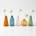 Les 5 couleurs de vase au choix dans le Cocon Duo : cône ambré, flacon bleu canard, cône rosé, sphère miel, fiole verte, avec leur bouquet en bois de sola